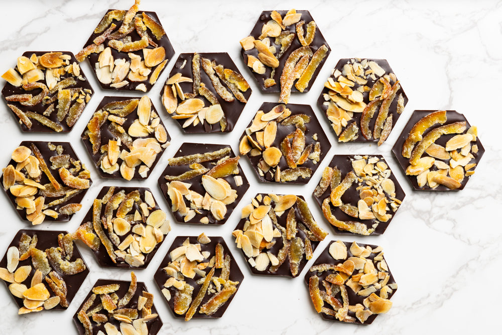 Open Citrus Almond Mendiants displaying handcrafted gourmet chocolate discs.